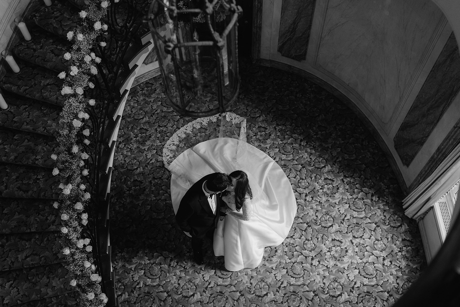 Birds eye view bride and groom kissing under a chandelier at Pine Hollow Country Club.