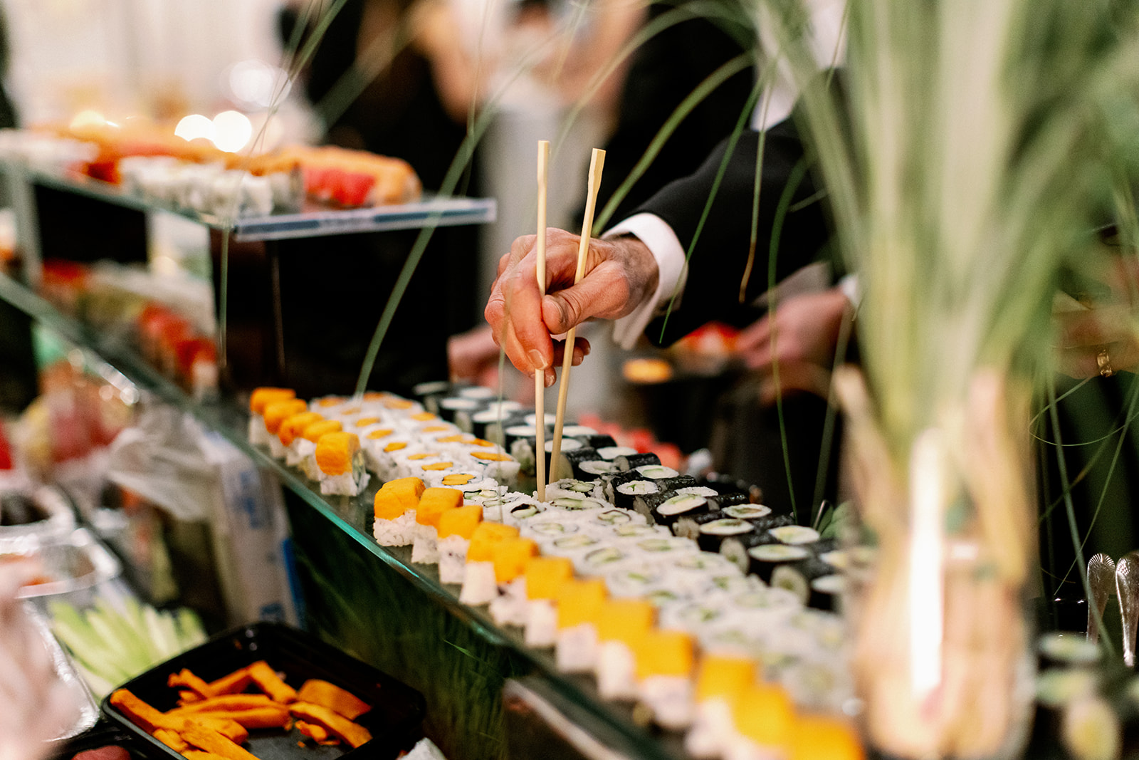 Wedding guests using chopsticks to pick up sushi. 