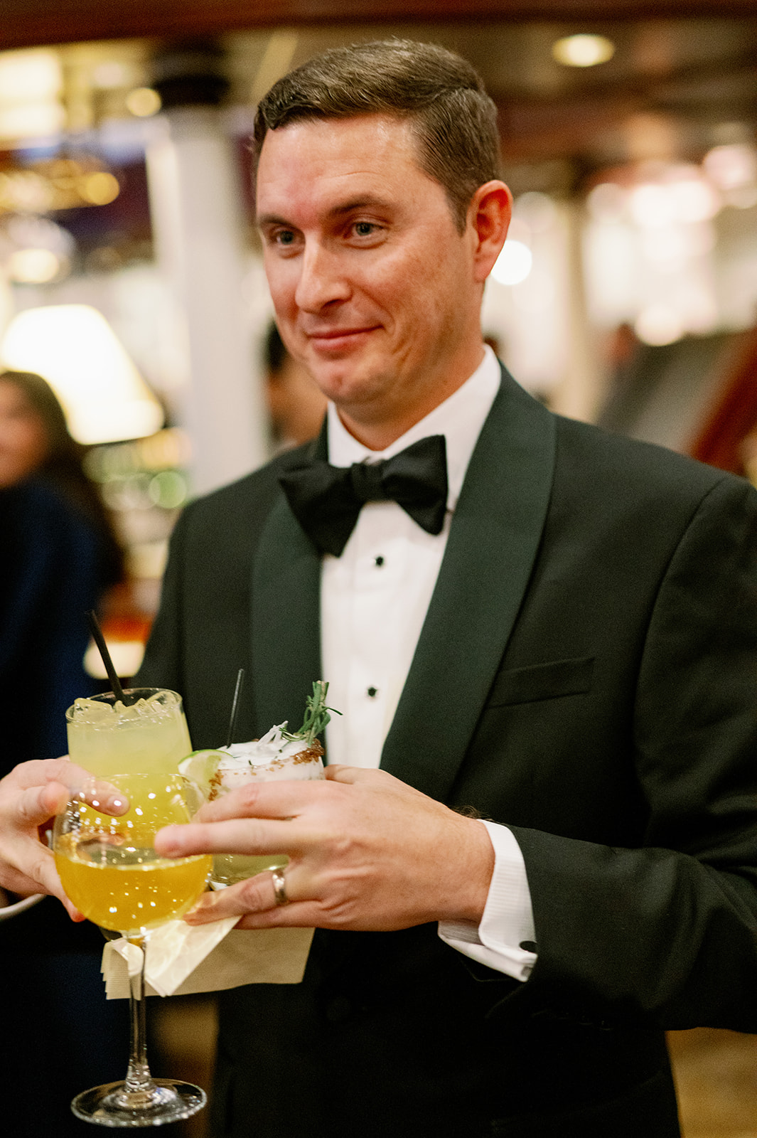 Wedding guest holding three drinks in his hand.