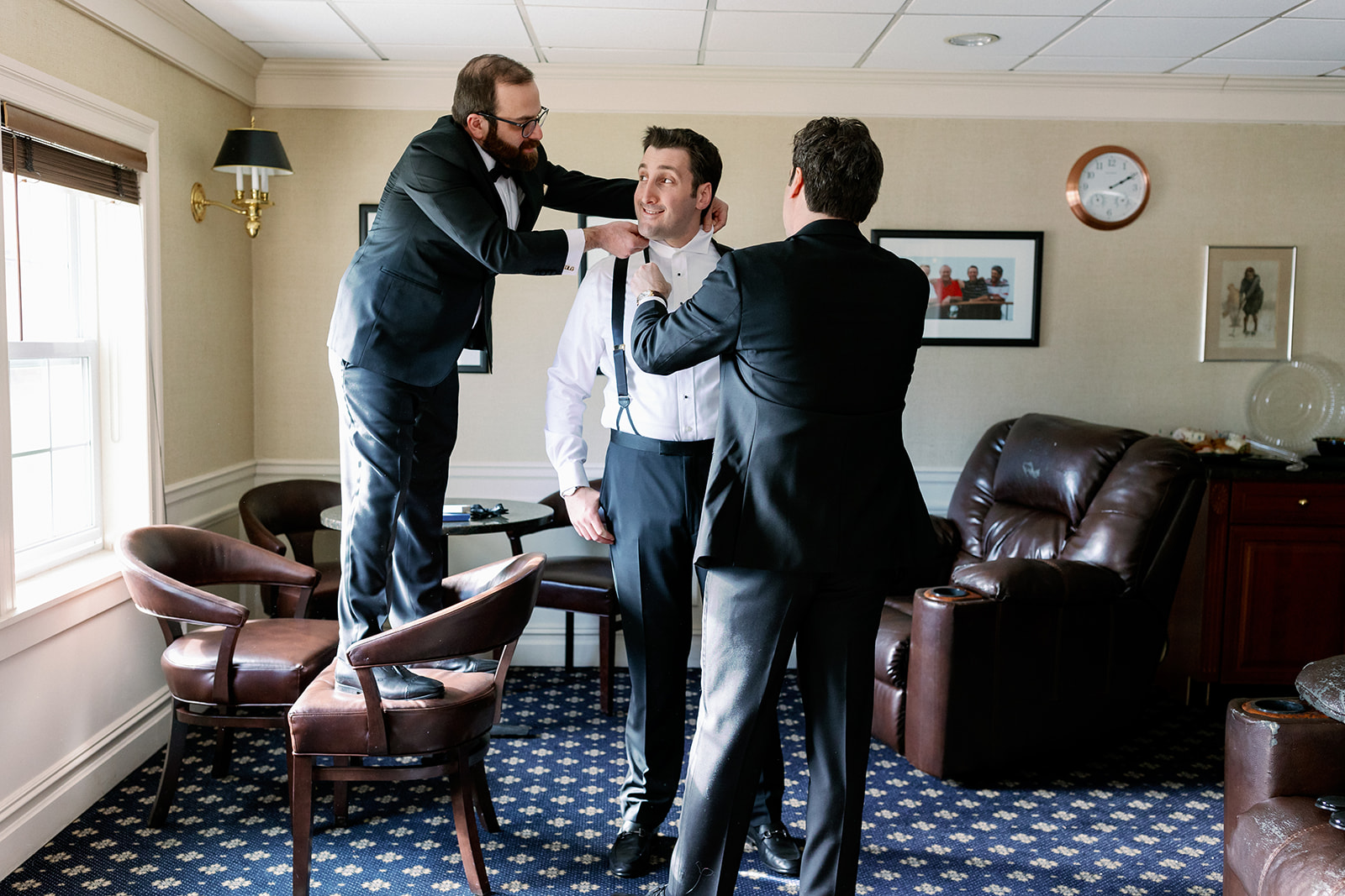 Groomsmen helping the groom get ready at Pine Hollow Country Club.