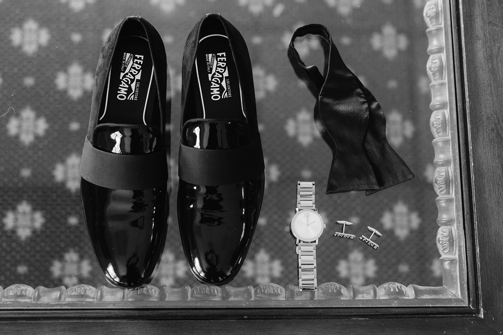 Black and white groom wedding detail flat lay with black loafers, bowtie and accessories. 