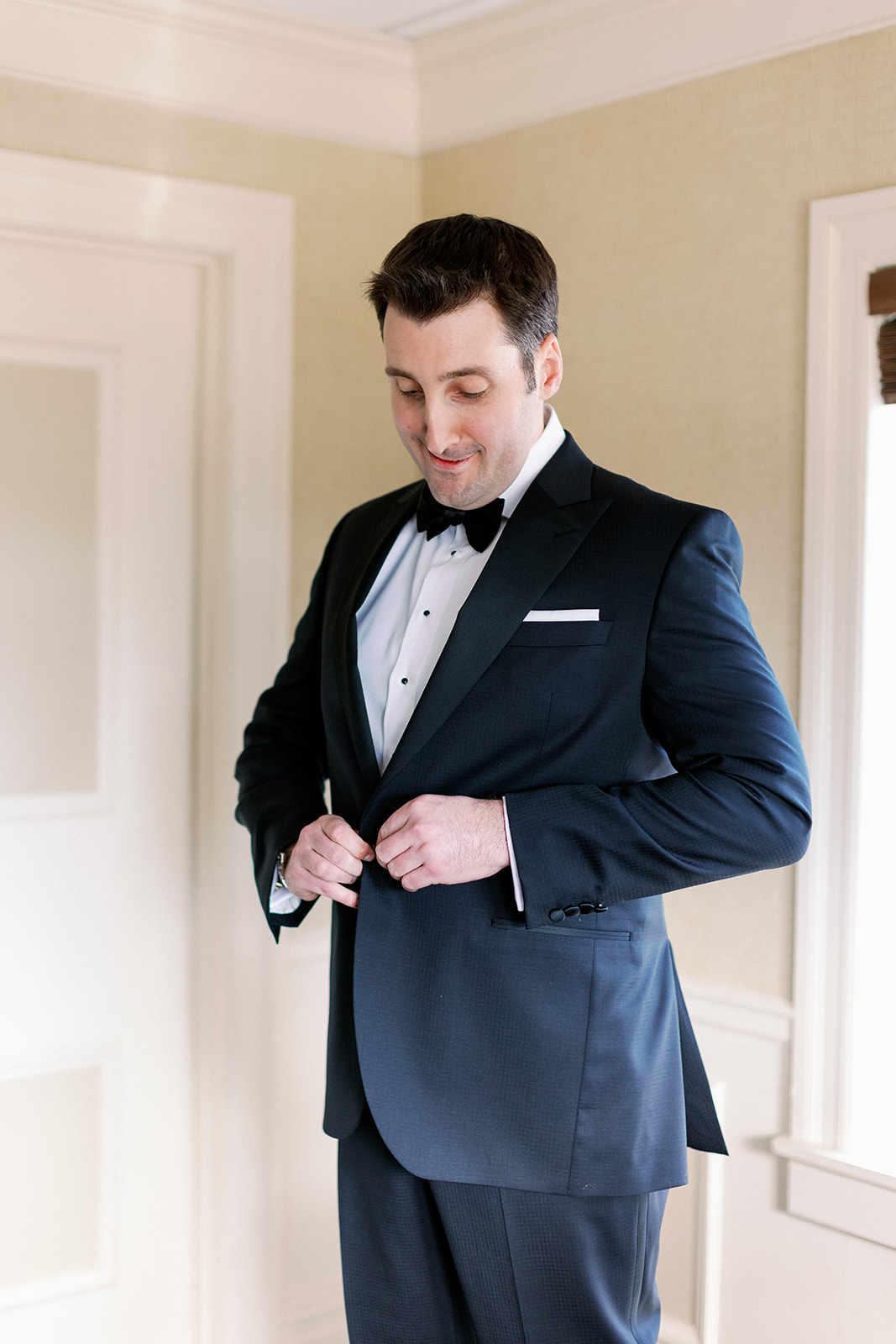 Groom getting ready putting on his suit jacket. 