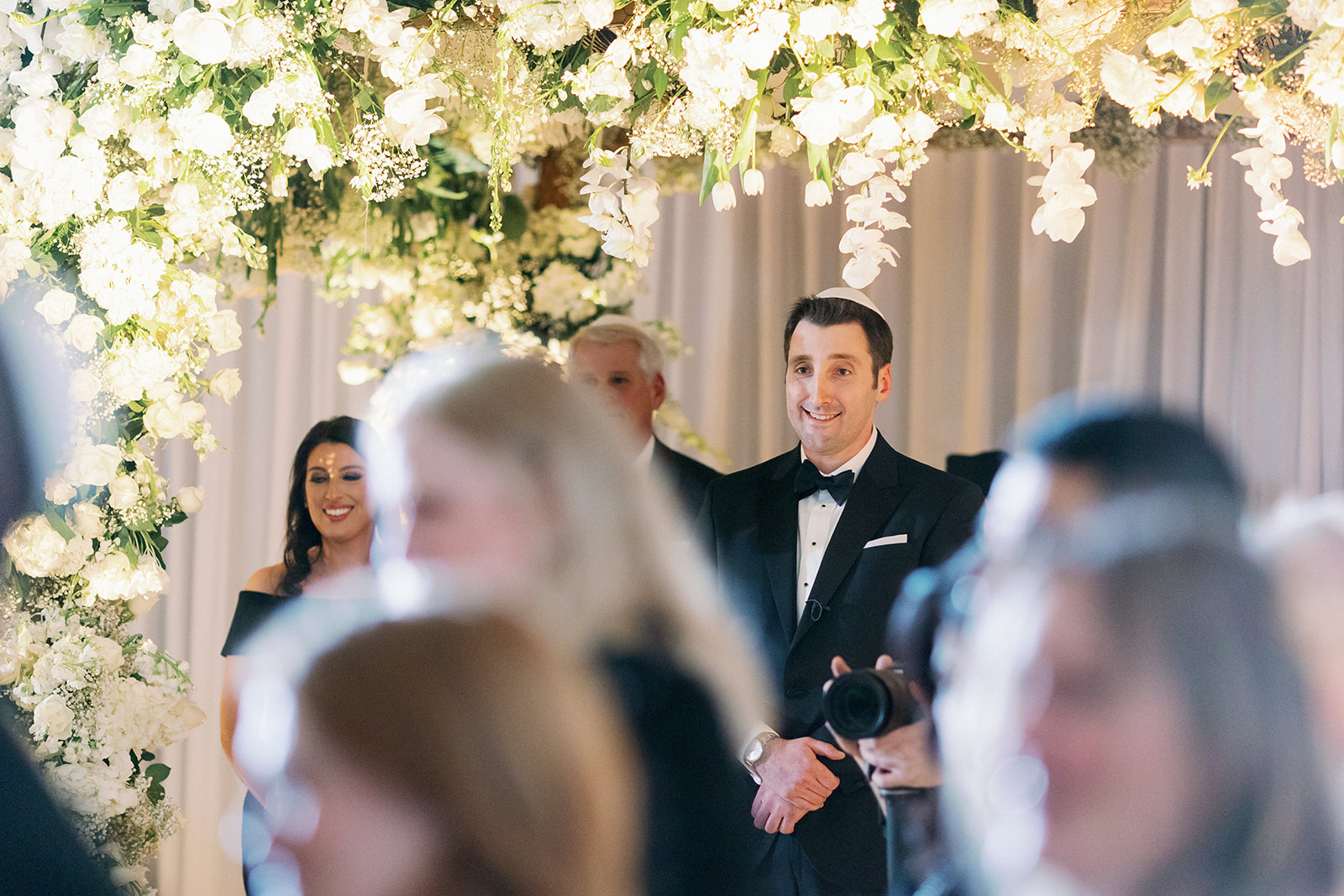 Groom smiling while watching his bride walk down the aisle.