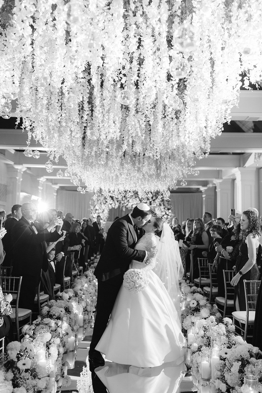 Bride and groom recessional kiss under a canopy of florals at Pine Hollow Country Club.