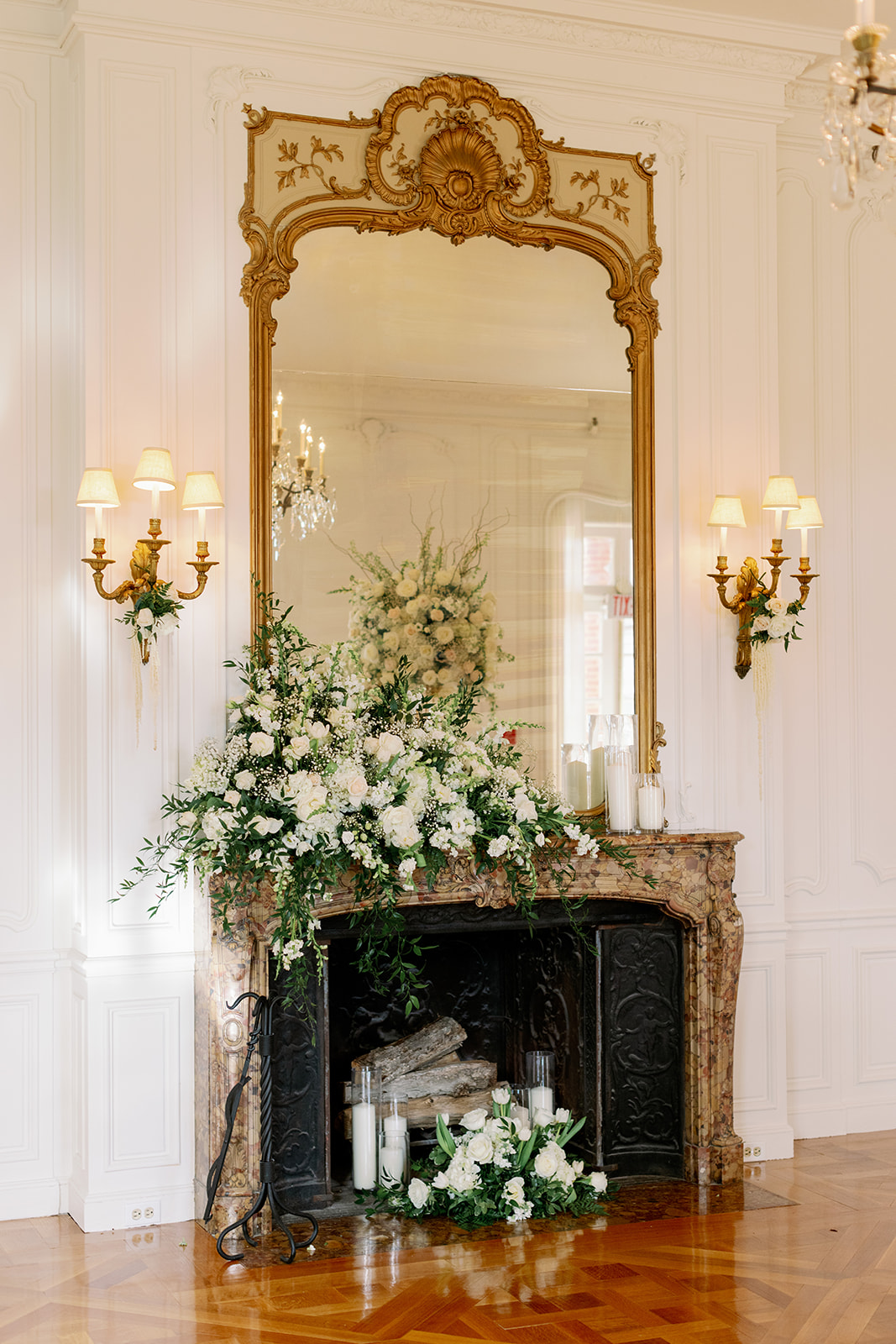 Grand fireplace with sconces and a large gold mirror decorated with florals at Pine Hollow Country Club.