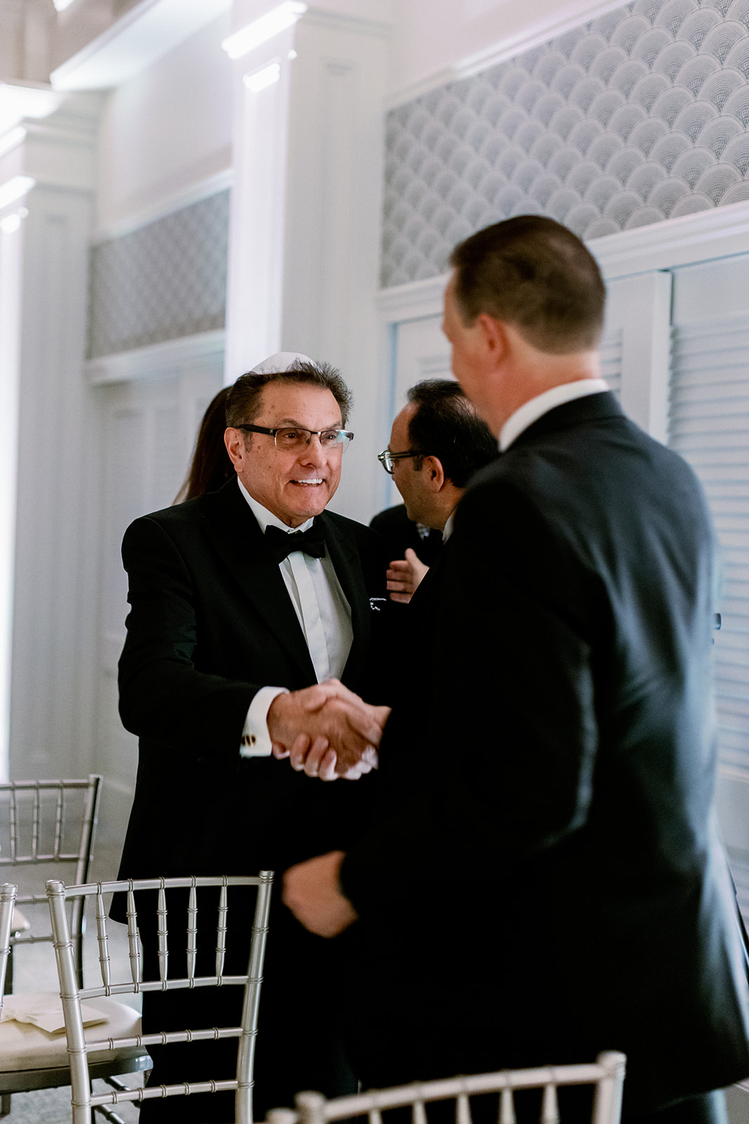 Candid moment of guests shaking hands pre-ceremony. 