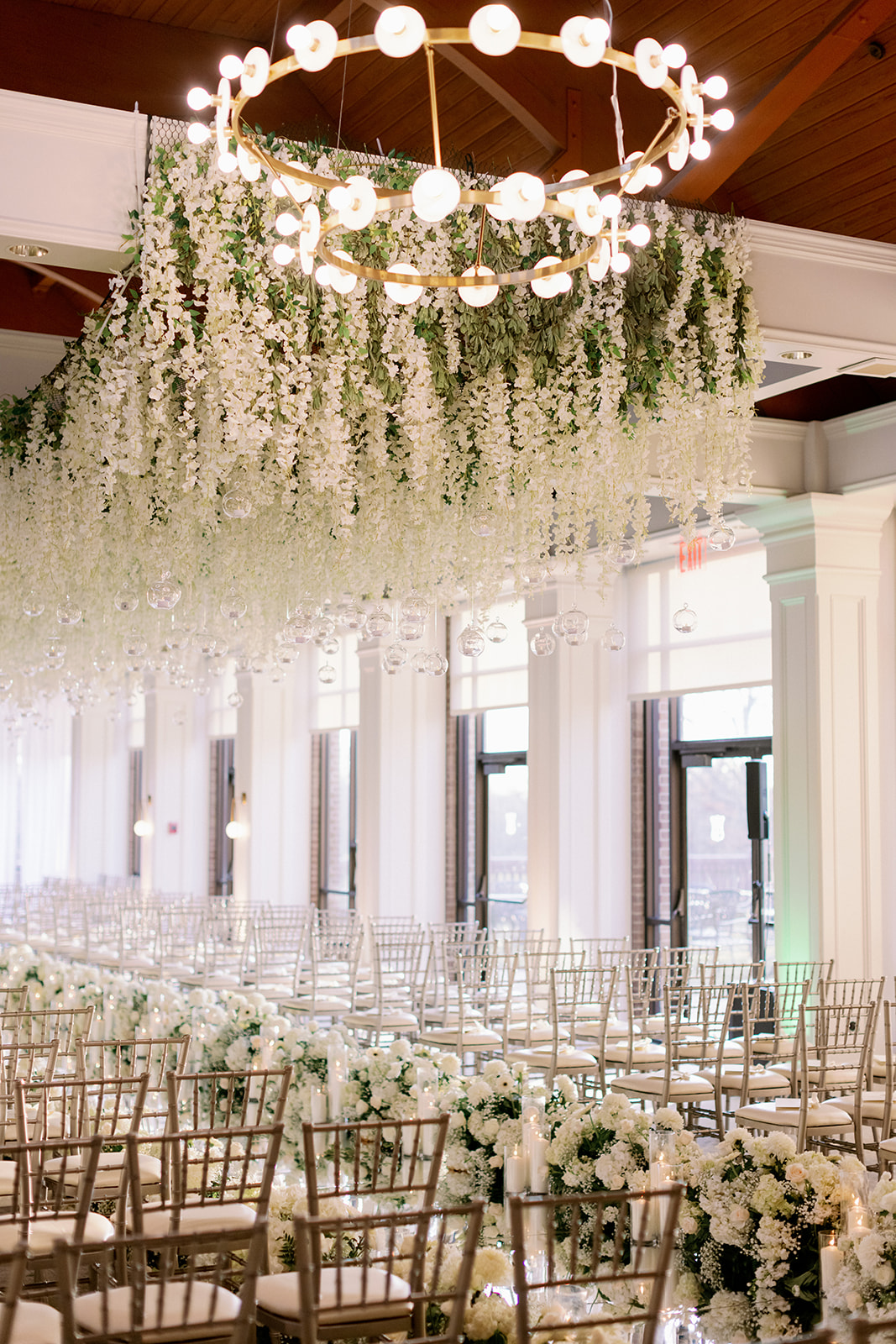 Indoor floral wedding ceremony with hanging installations and chiavari chair at Pine Hollow Country Club.