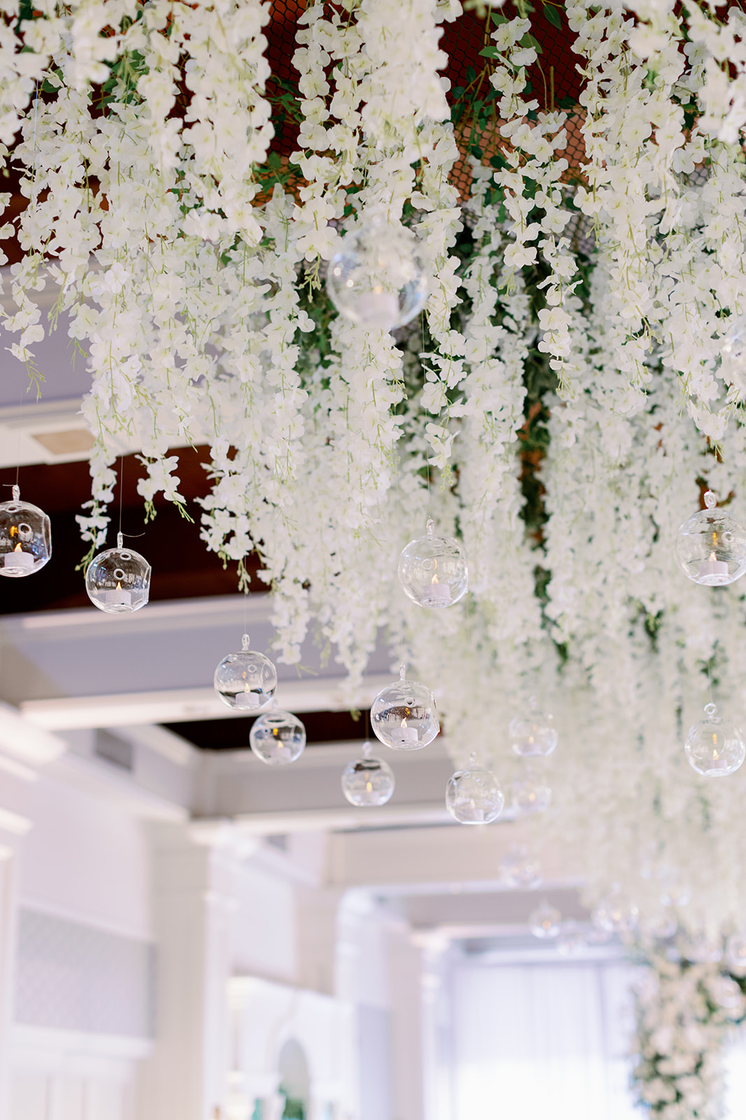 White floral wedding ceremony hanging installation with bulb lights. 
