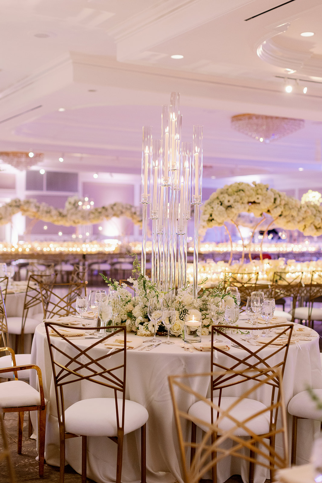 Luxury glam wedding reception with gold accents, large floating floral installations and glass centerpieces. 