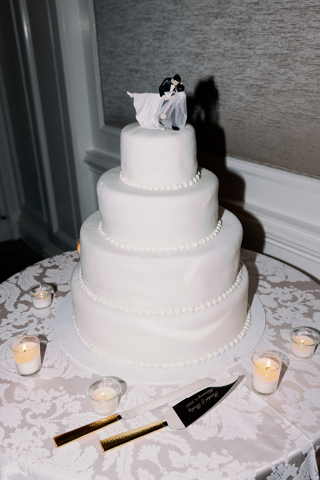 4-tier classic white wedding cake with bride and groom topper direct flash photo.