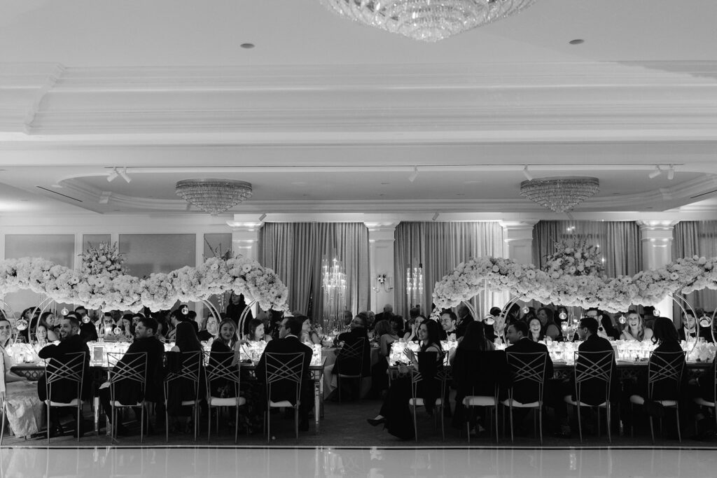 Wide angle view of Pine Hollow Country Club wedding reception dinner with floating floral centerpieces. 