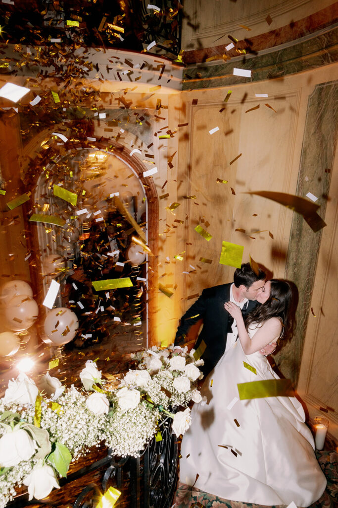 Bride and groom kissing under falling confetti at Pine Hollow Country Club.