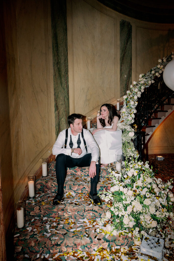 Bride and groom sitting on the stairs at Pine Hollow Country Club after their reception.