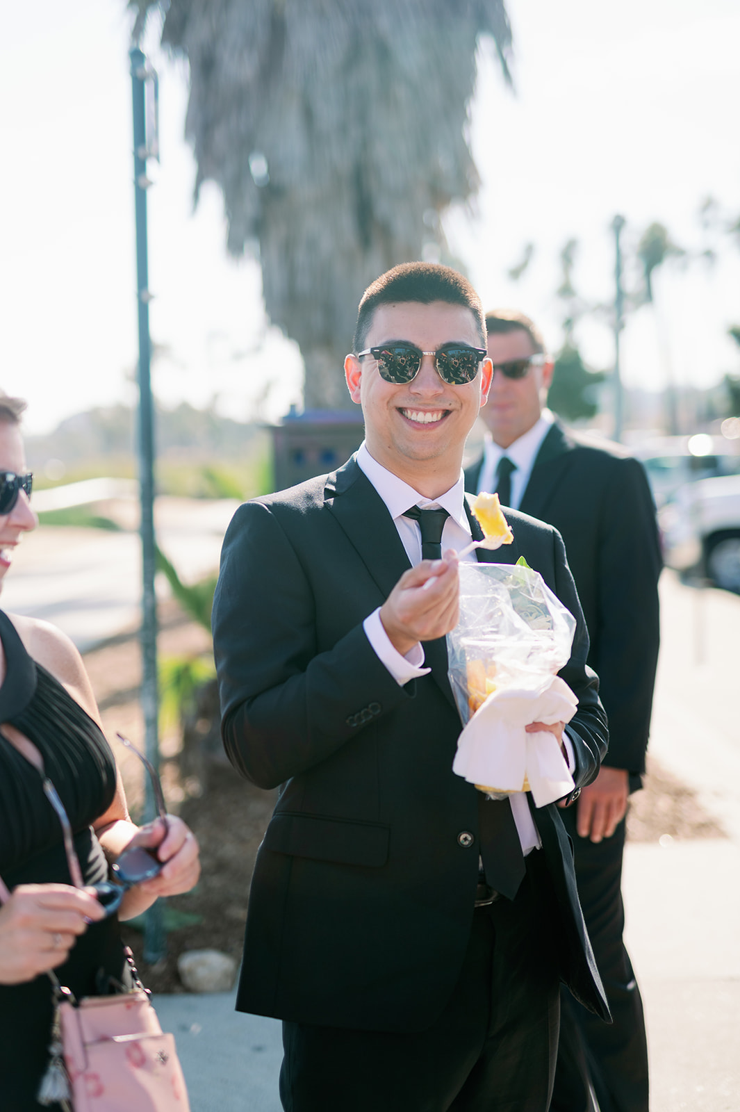 Wedding guest eating fruit and wearing sunglasses. 