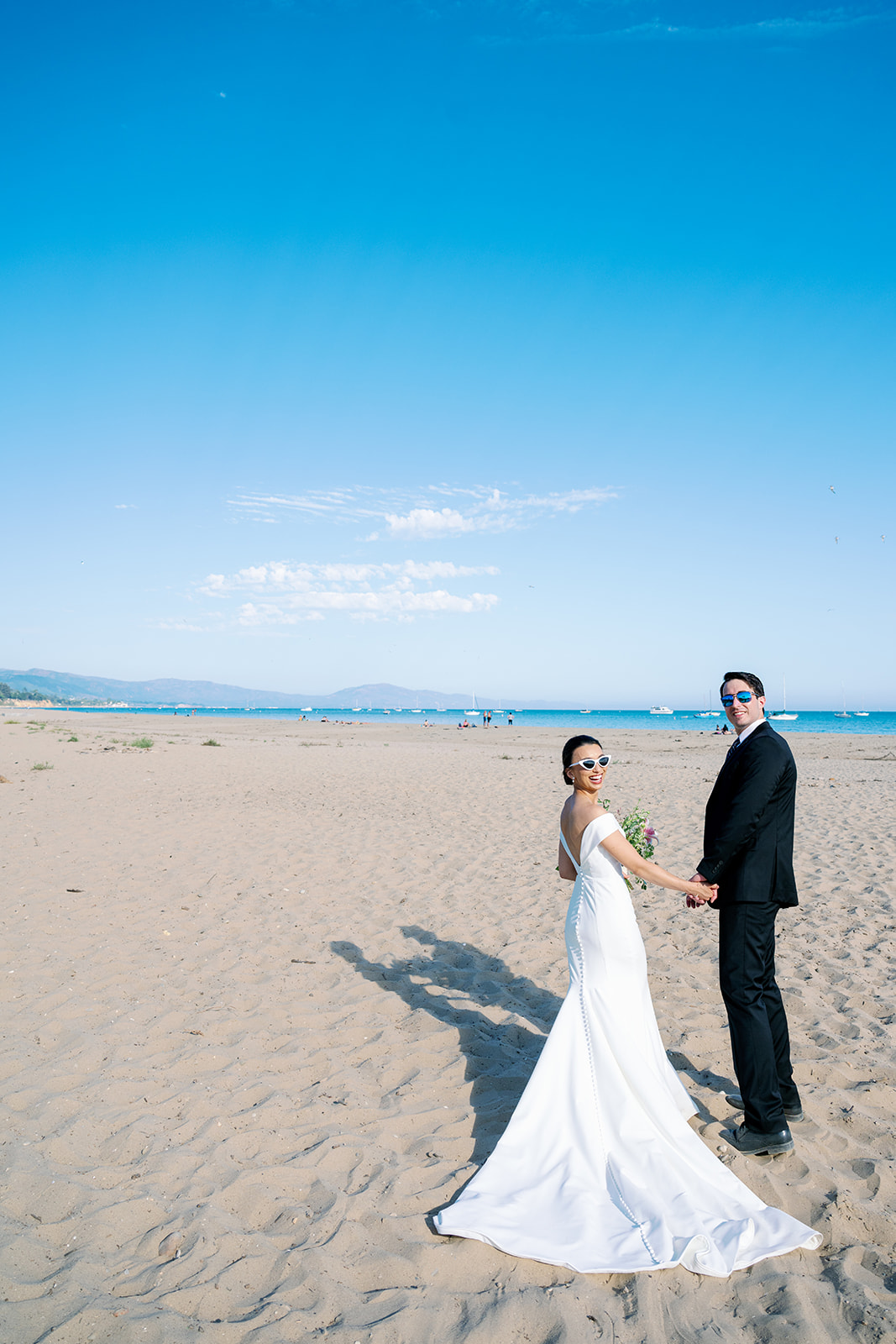 Bride and groom wearing sunglasses on the beach in Santa Barbara. 