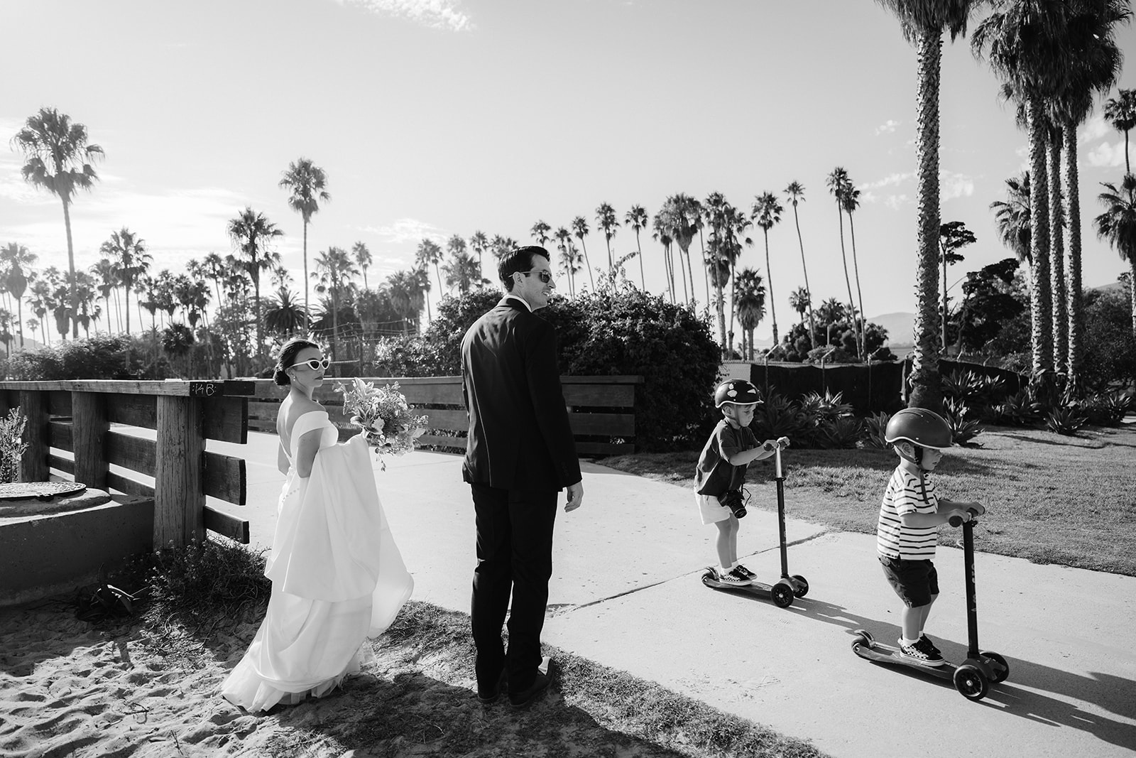 Bride and groom walking on the sidewalk in Santa Barbara by the beach. 