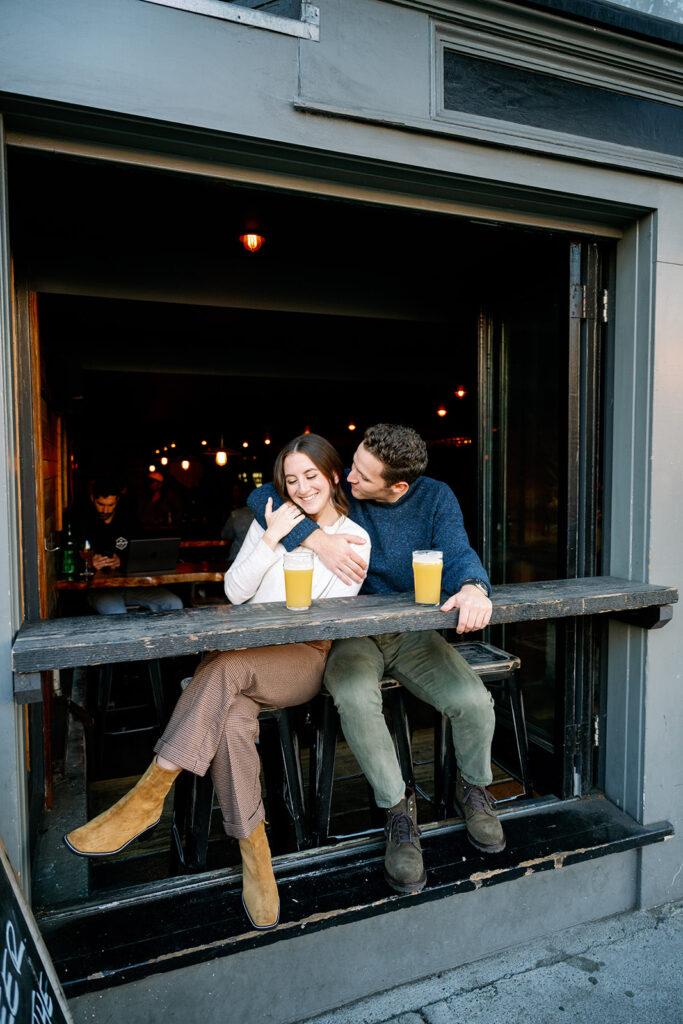 Couple embracing at a bar in downtown San Francisco for their engagement photoshoot. 