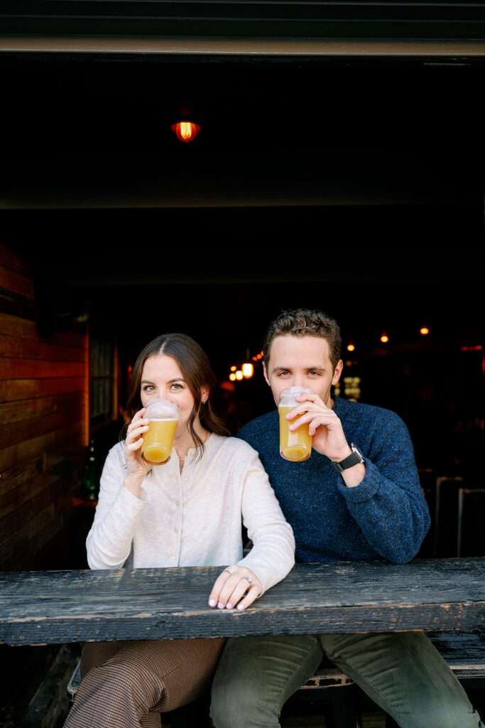 Couple drinking a beer at a downtown  bar during their engagement session.