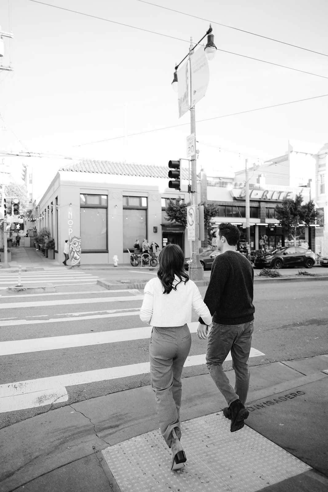 Couple walking on a crosswalk in downtown San Francisco during their cinematic engagement session.