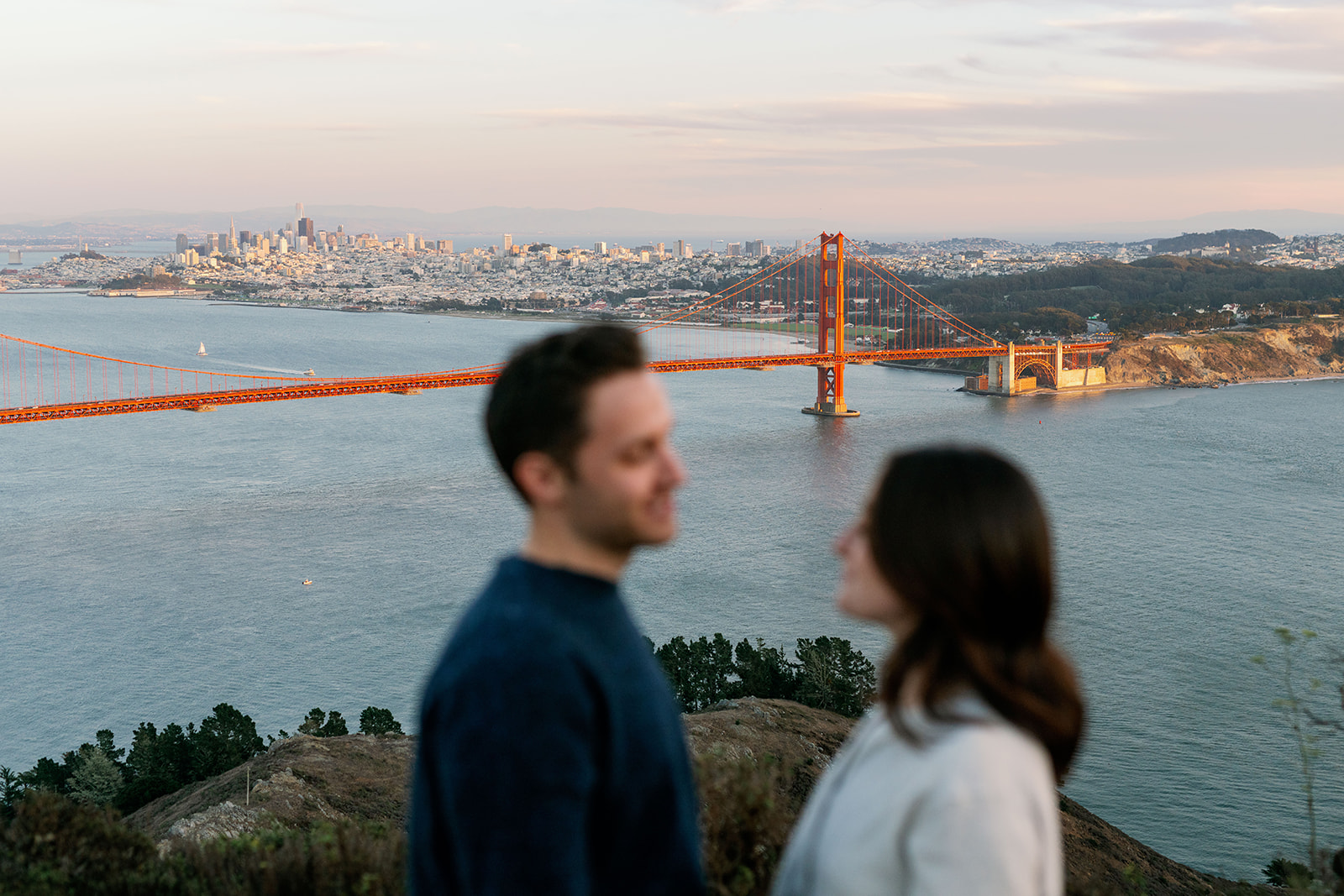 Couple out of focus with the Golden Gate Bridge in the background. 