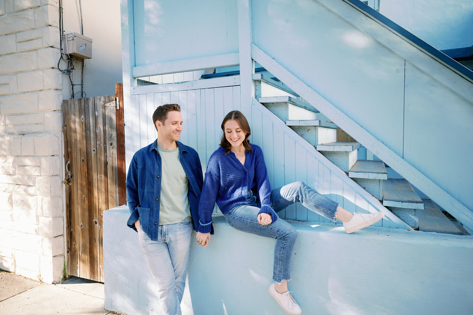 Candid couple posing against blue stairs near their home in Hayes Valley, San Francisco. 