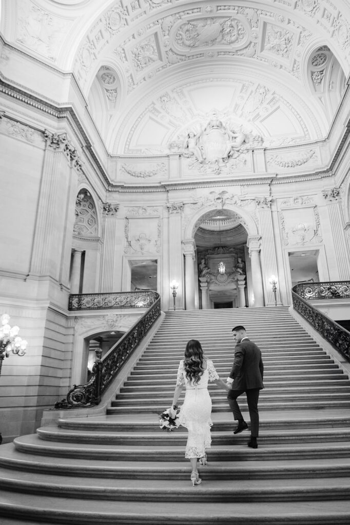 Couple walking up the grand staircase at SF City Hall. 