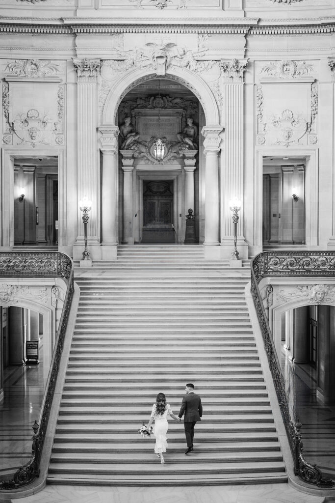 Bride and groom walking up the grand staircase at San Francisco City Hall.