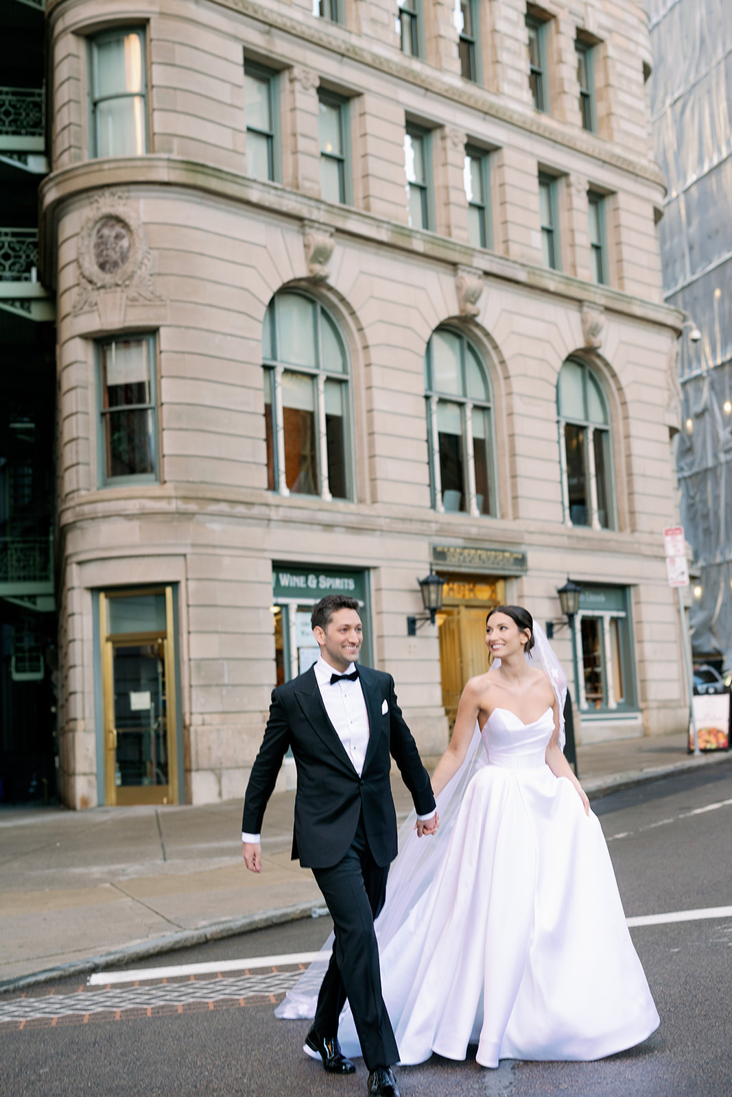 Bride and groom crossing the street toward their venue The State Room in Boston. 
