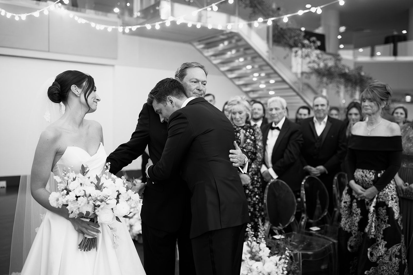 Groom hugging the bride's dad during a Boston State Room wedding ceremony.