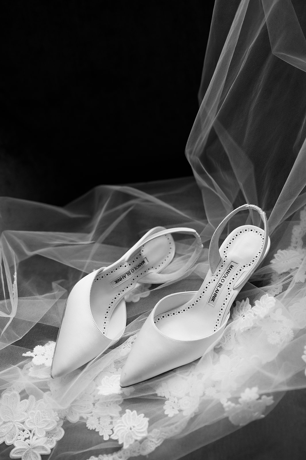 Editorial black and white detail shot of the bride's veil and Manolo Blahnik pumps.