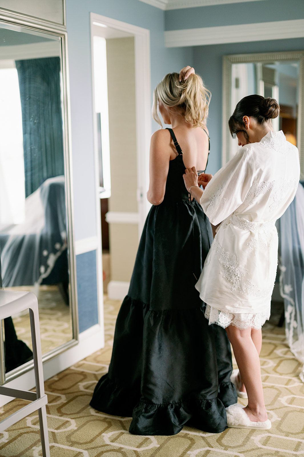 Bride helping her maid of honor with her dress candid getting ready photo. 