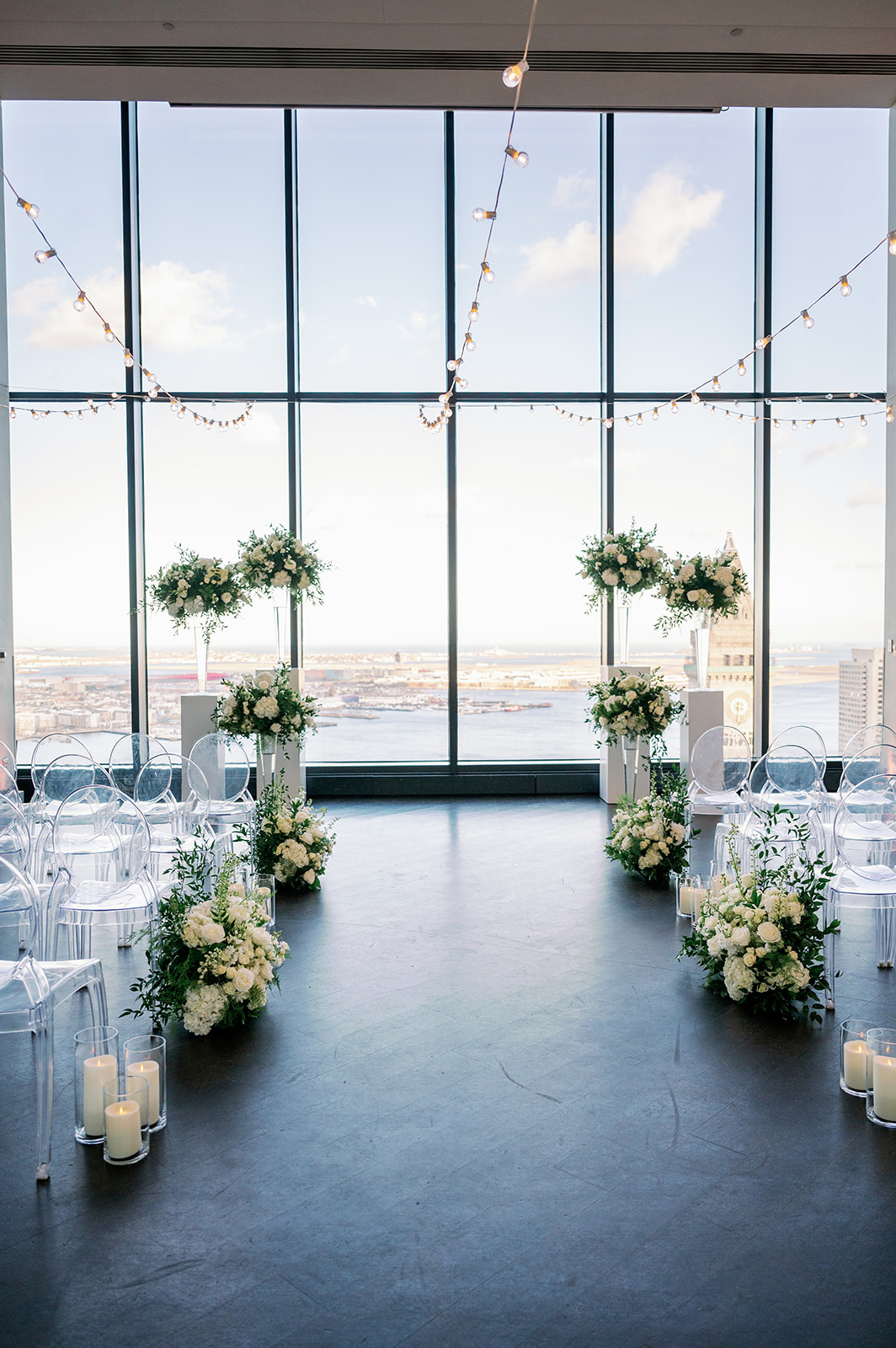 Boston State Room wedding ceremony with white floral arrangements overlooking the city. 