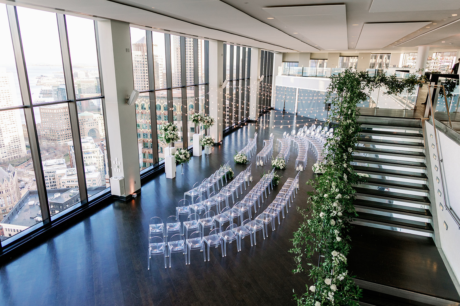 Boston State Room wedding ceremony setup with cascading greenery and ghost chairs.
