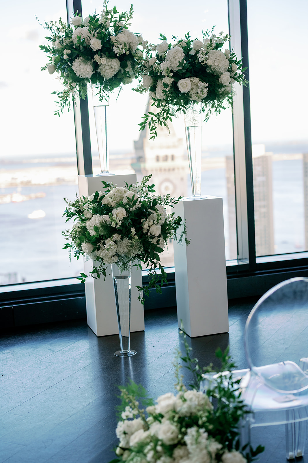 Winter wedding ceremony backdrop with elegant floral arrangements on white pedestals at the State Room in Boston.