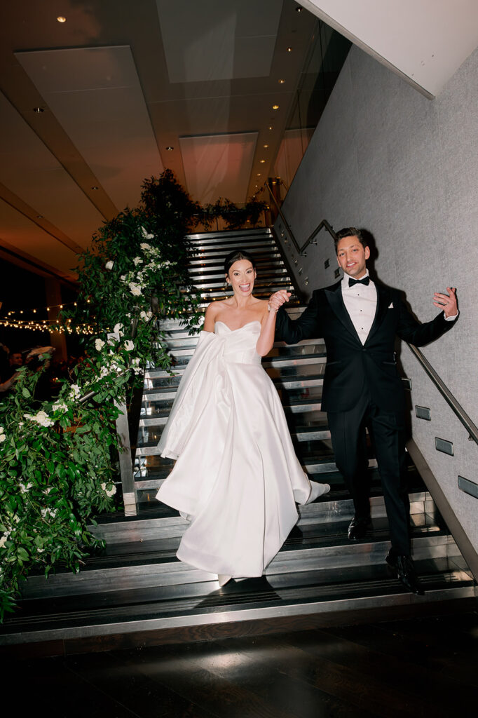 Bride and groom making their grand entrance down the staircase for their Boston State Room wedding reception.