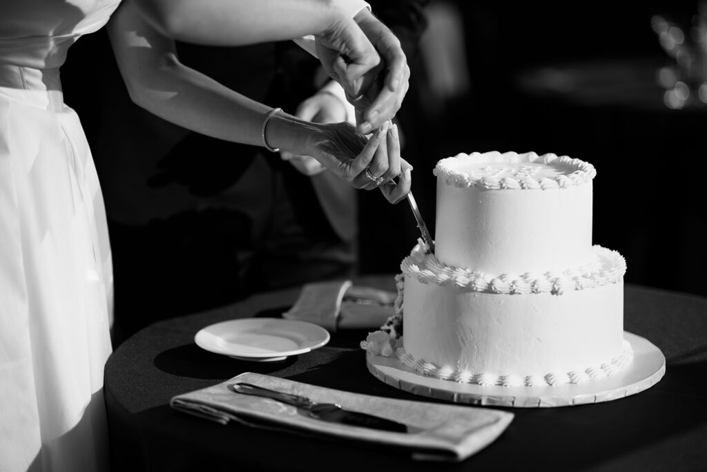 Bride and groom cutting their elegant two tier white wedding cake.