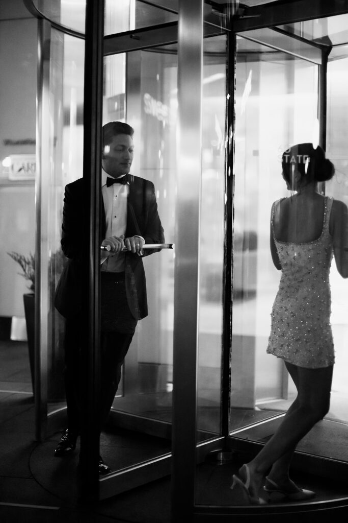 Bride and groom candidly using a revolving door at 60 State Street in Boston.