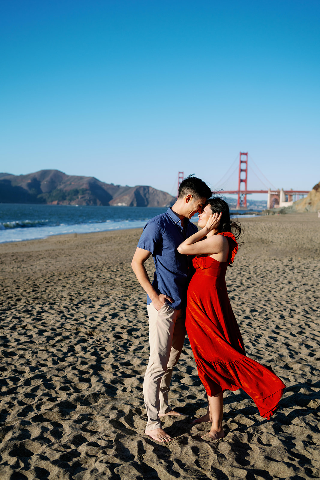 Sunset engagement photoshoot at Baker Beach in San Francisco with the Golden Gate Bridge in the background. 